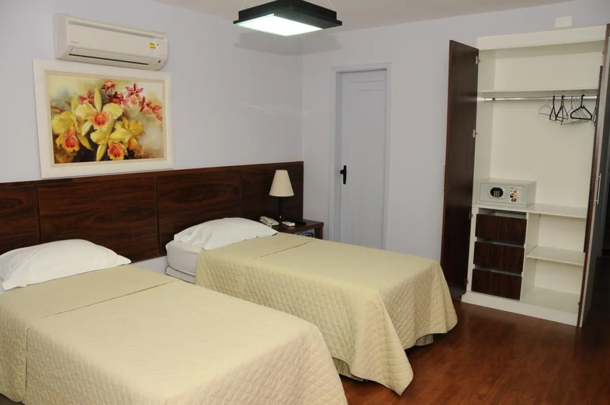 Quarto Superior do Gallant Hotel com duas camas e poltrona